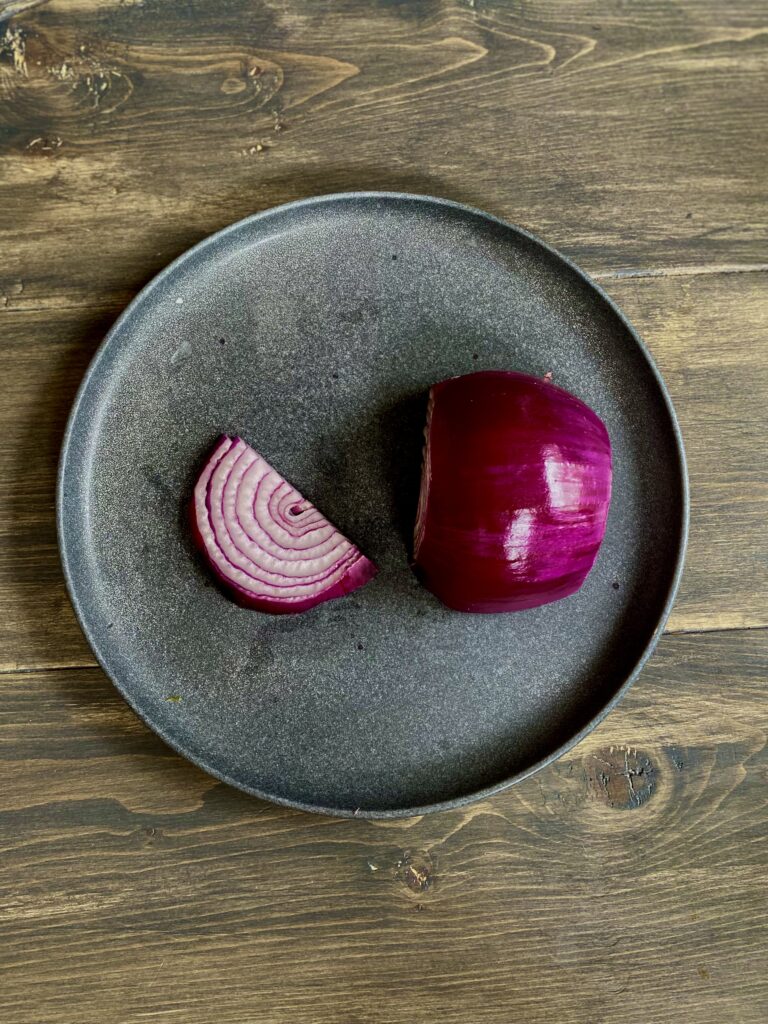 Half of the onion laid on flat side and sliced long ways.