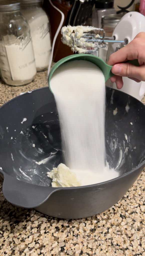 Adding sugar to large bowl with beaten butter.