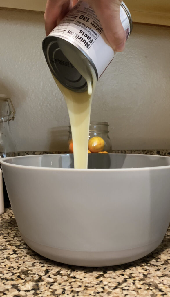 Mixing heavy whipping cream into the condensed milk and evaporated milk mixture.