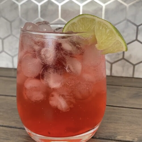 Cherry limeade in a glass with a lime slice for decorations.