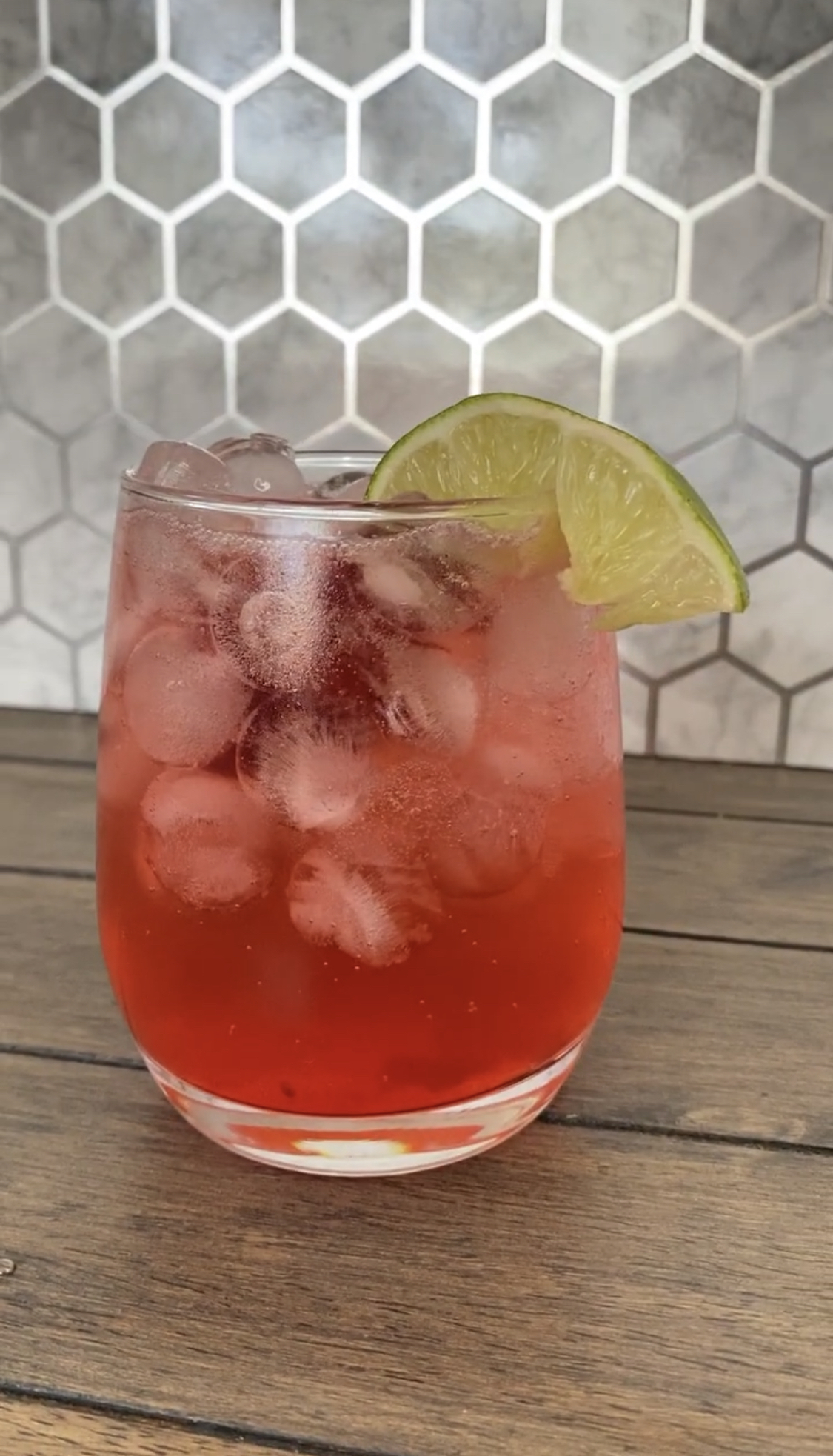 Cherry limeade in a glass with a lime slice for decorations.