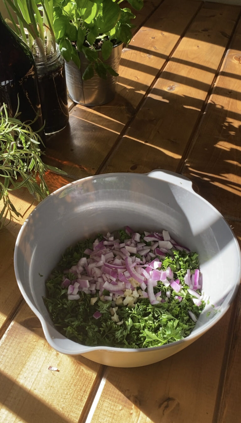 Parsley, Cilantro, Red Onion, and Garlic combined together in a bowl.