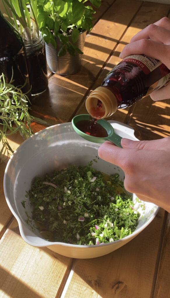 Red wine vinegar is poured into a measuring spoon.