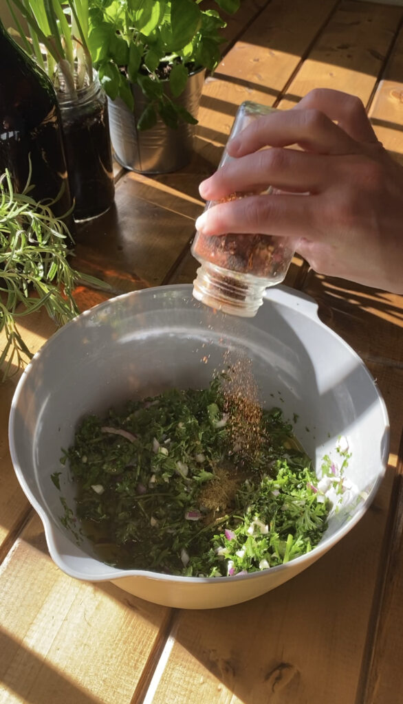 Red pepper flakes are being shaken onto the Chimichurri.