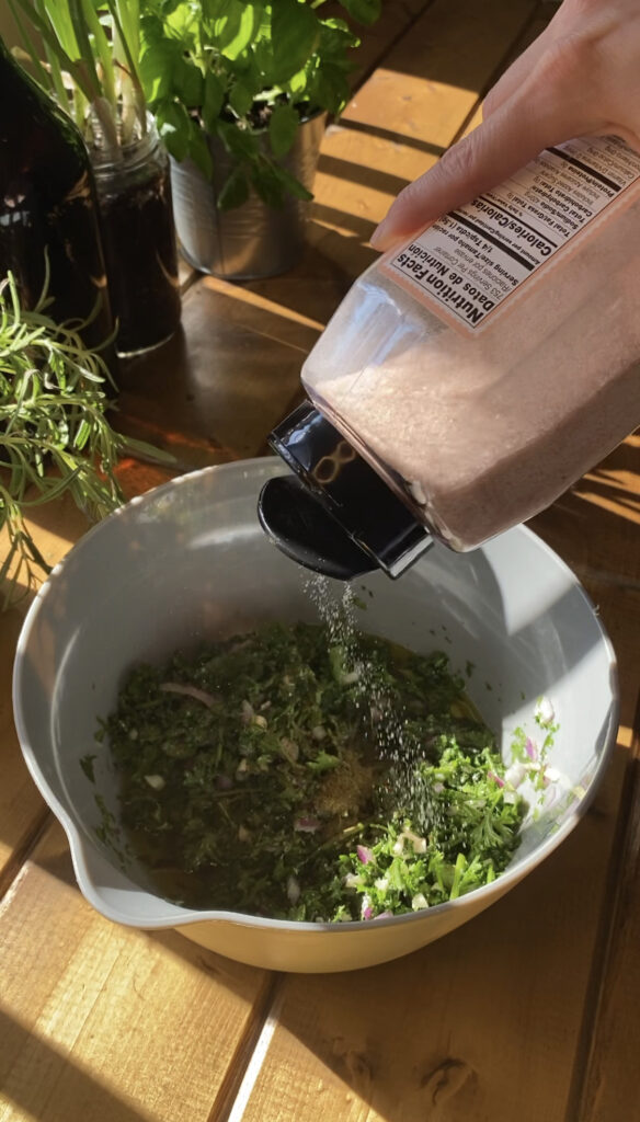 Pink Himalayan salt being shaken onto mixture.