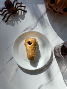 Raspberry Cheese Danish on a plate with a spider near by