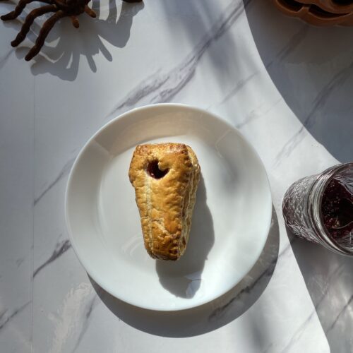 Raspberry Cheese Danish on a plate with a spider near by