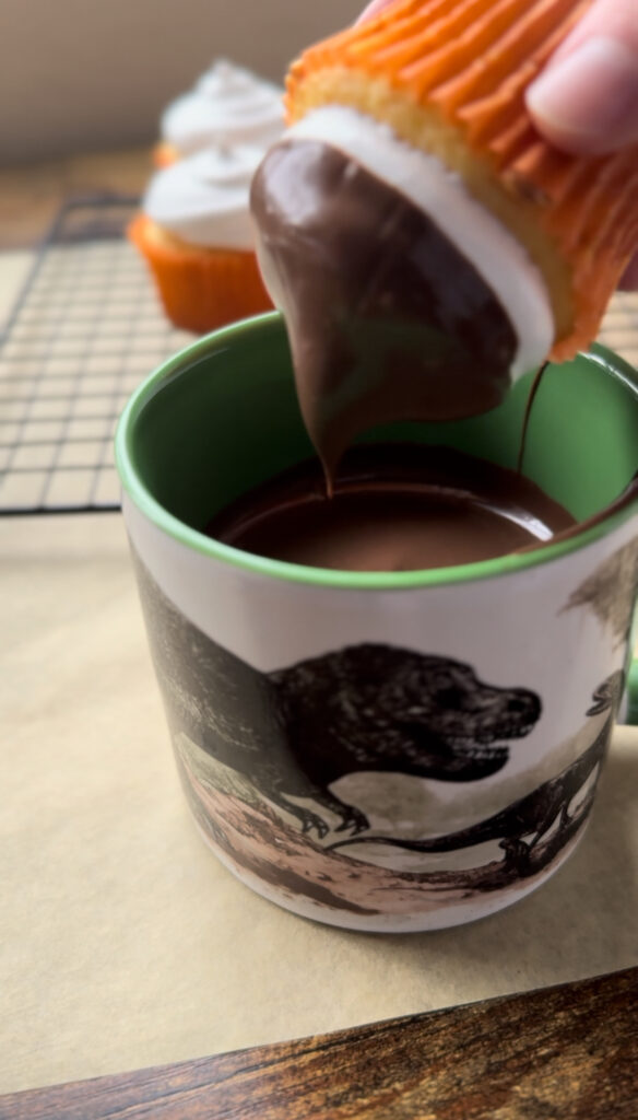 Dipping a hi-hat frosted cupcake in melted chocolate.