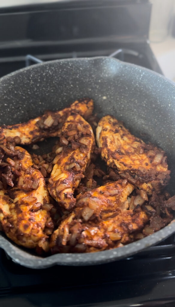 Chicken coated in flour in frying pan with onion mixture browned on both sides for chicken paprikash