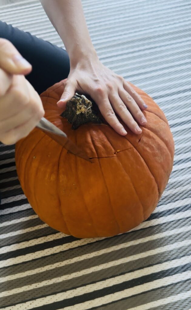 Cutting the top of a pumpkin off with a sharp knife