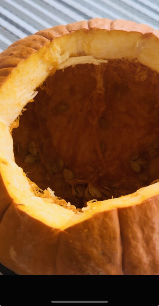 Showing the inside of a pumpkin being cleaned of the guts and seeds.