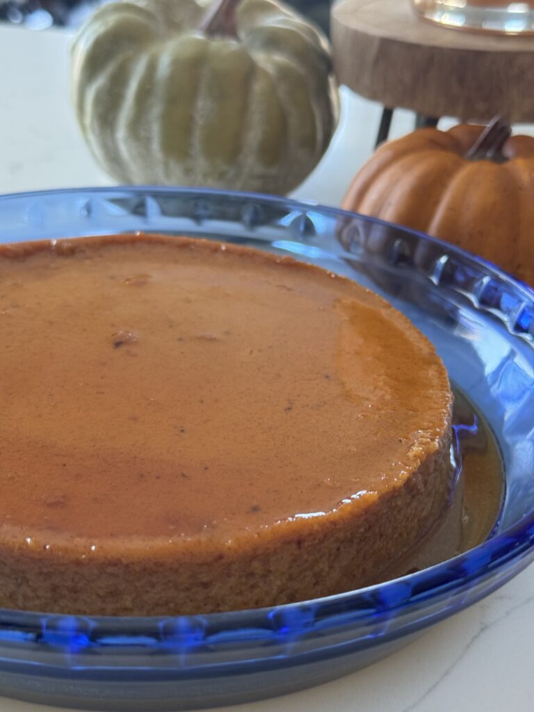 Creamy pumpkin flan topped with golden caramel sauce on a white plate — the perfect Mexican American Thanksgiving dessert