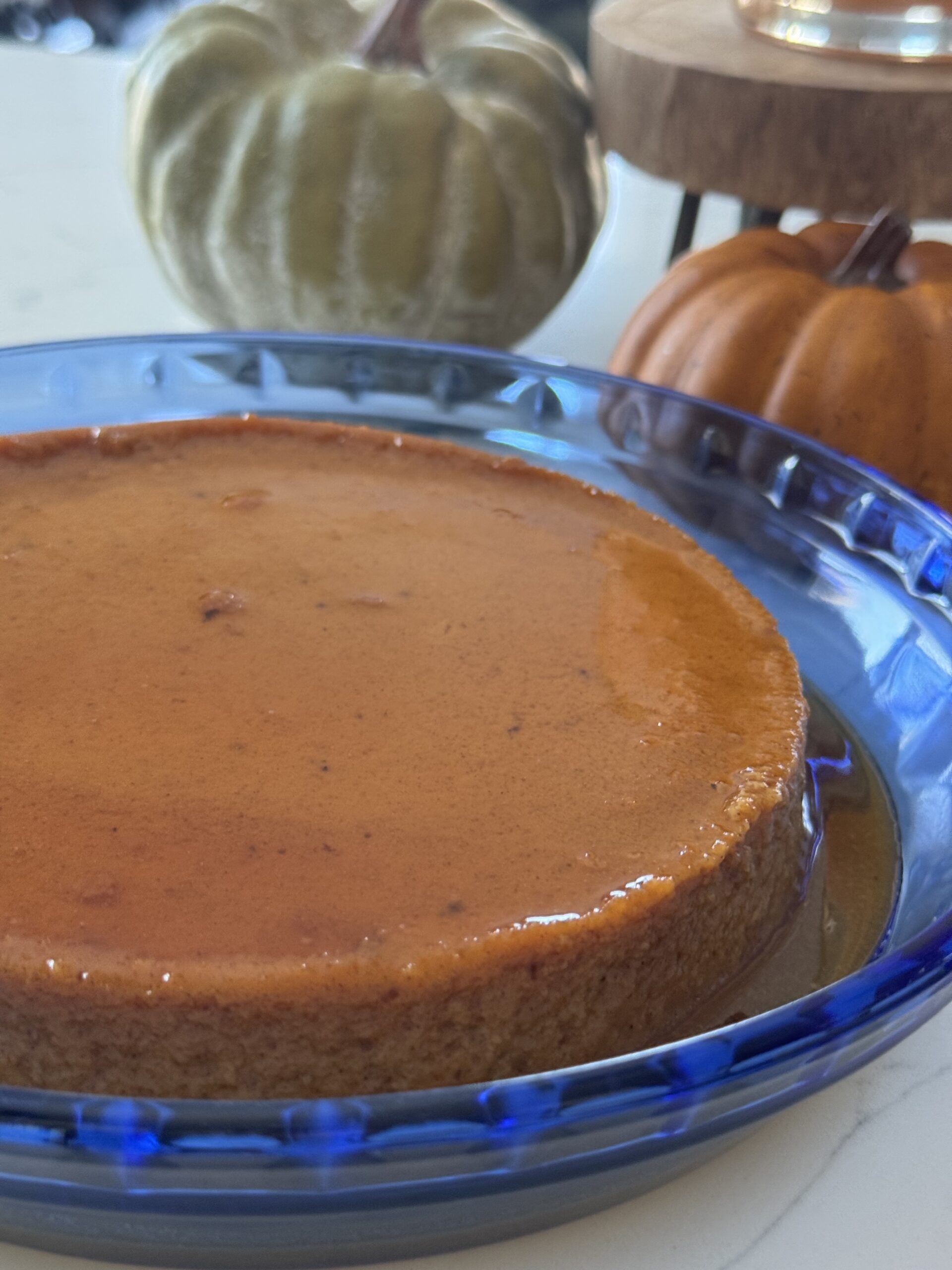 Creamy pumpkin flan topped with golden caramel sauce on a white plate — the perfect Mexican American Thanksgiving dessert