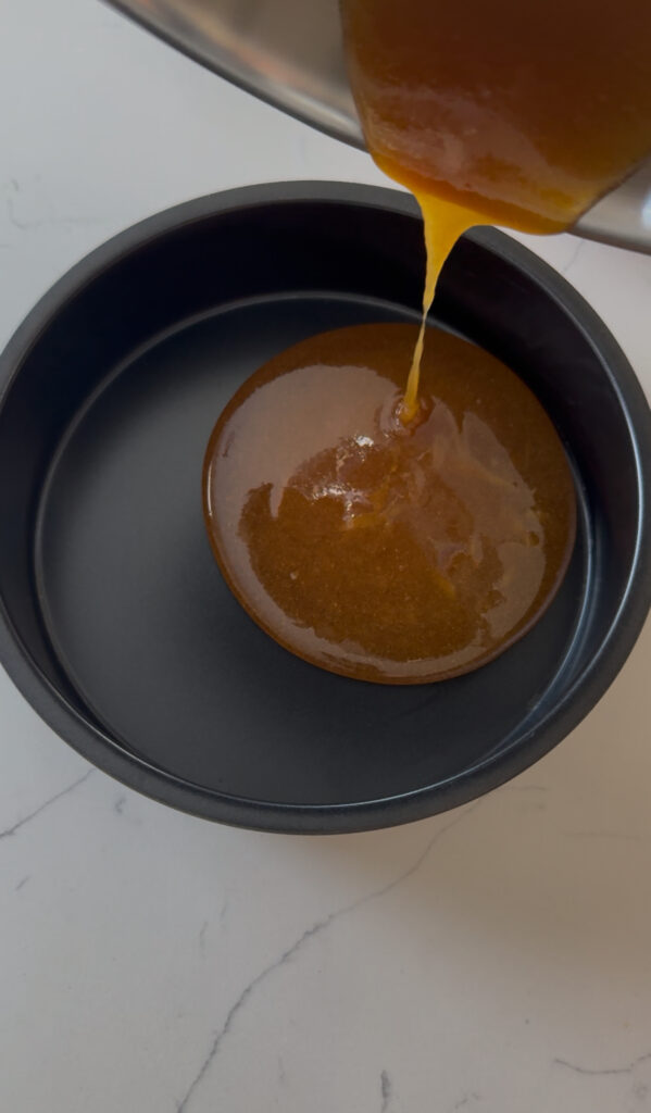 Pouring honey golden caramel into the bottom of a pan for flan