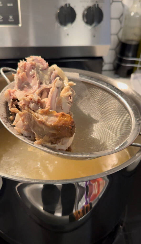 straining the chicken bones from the chicken broth