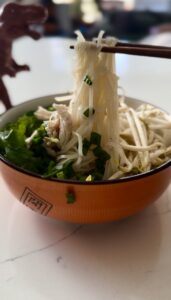 holding noodles up for chicken pho with chopsticks