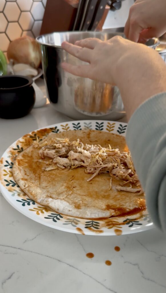 filling the enchiladas with the shredded chicken mixture