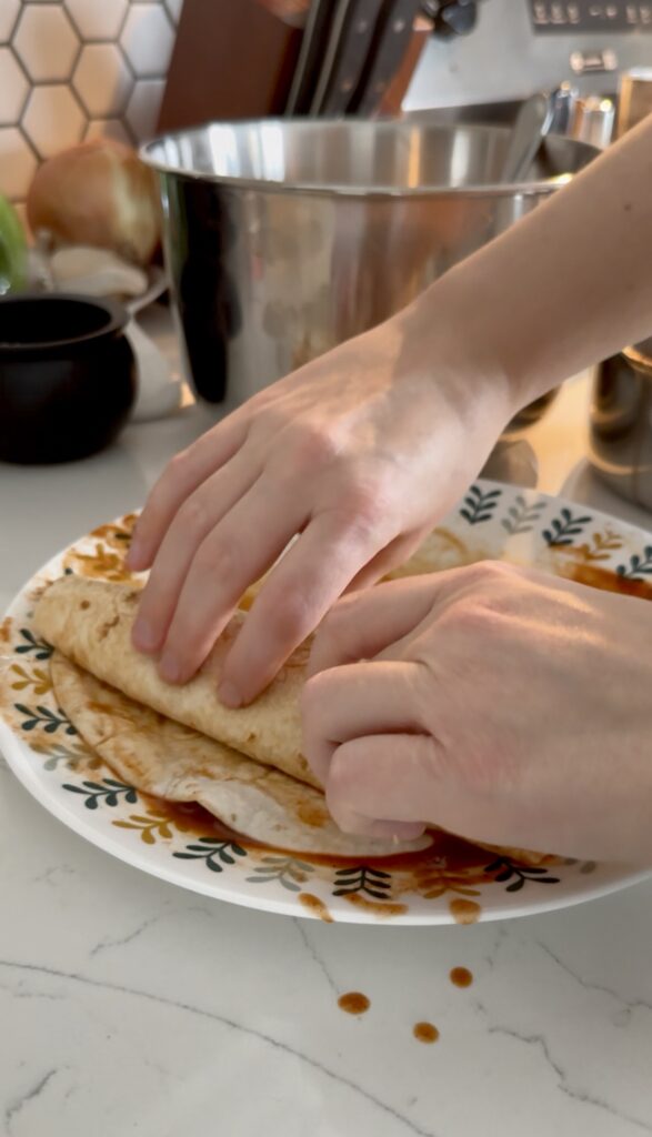 Fully rolled chicken enchilada on a plate.