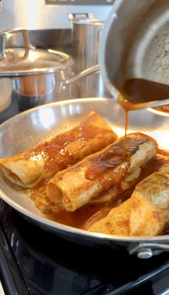 pouring red sauce on chicken enchiladas