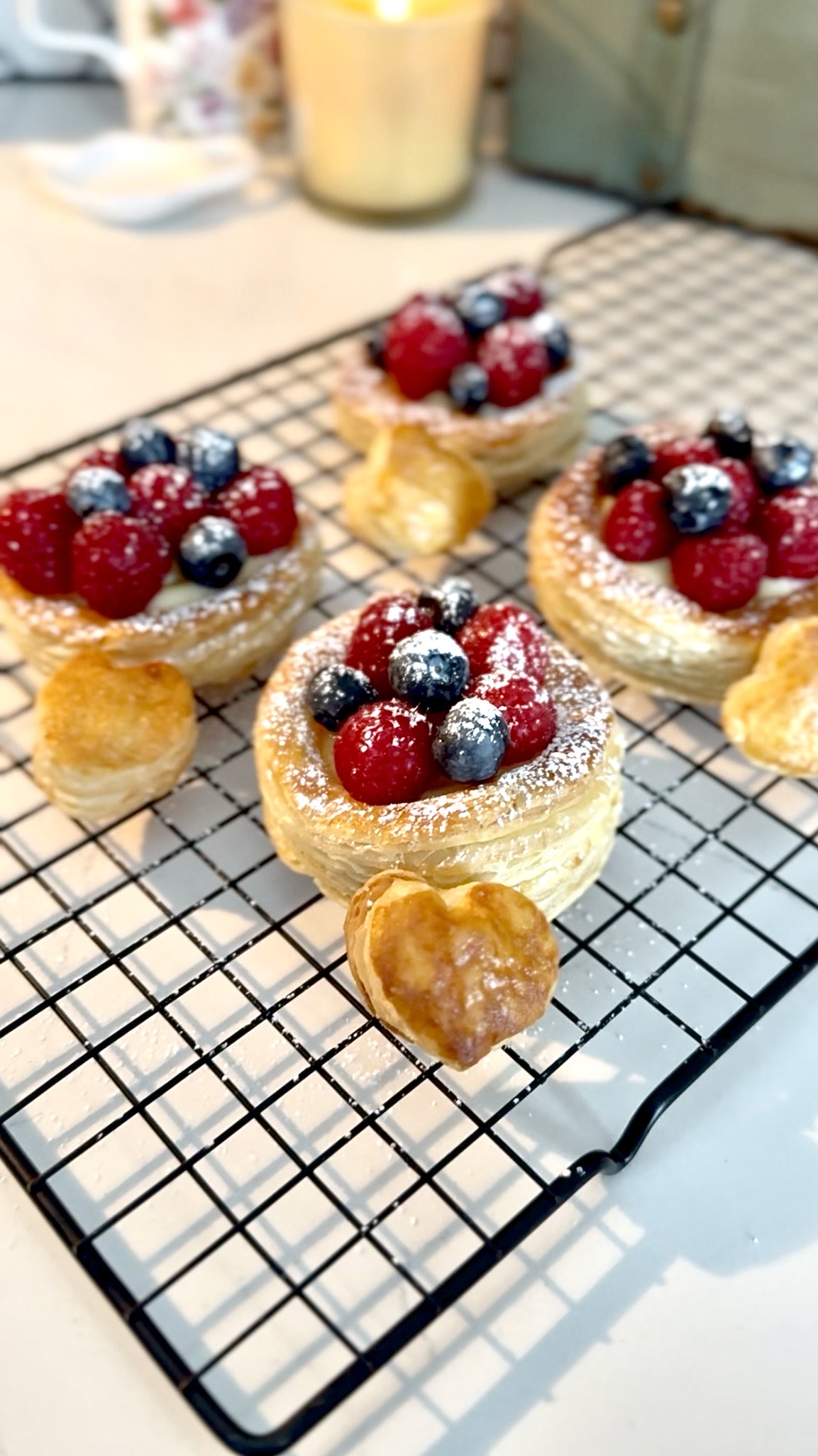 Four flaky pastries topped with custard, raspberries, blueberries and spinkle of powdered sugar.