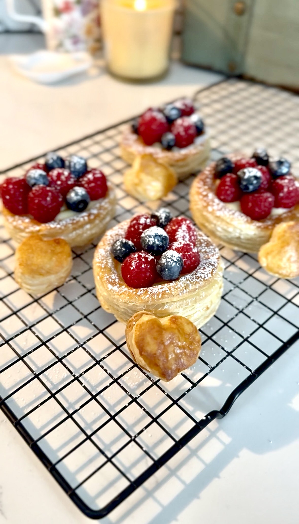 Four flaky pastries topped with custard, raspberries, blueberries and spinkle of powdered sugar.