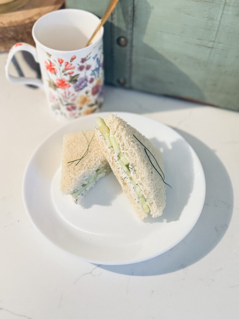 cucumber tea sandwiches served on a plate neatly with a cup of tea