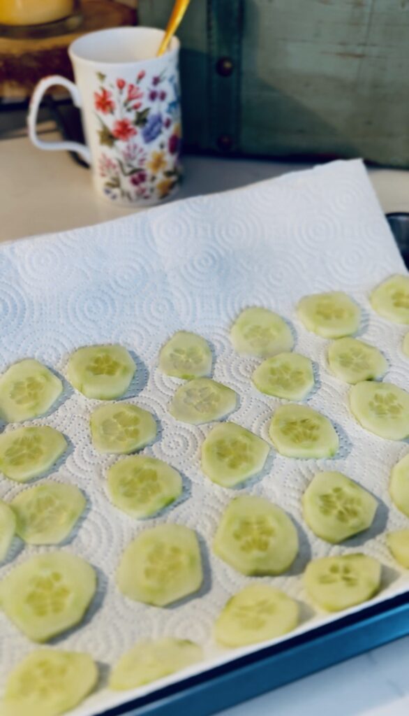 slices of english cucumber on a tray topped with sea salt to draw out moisture