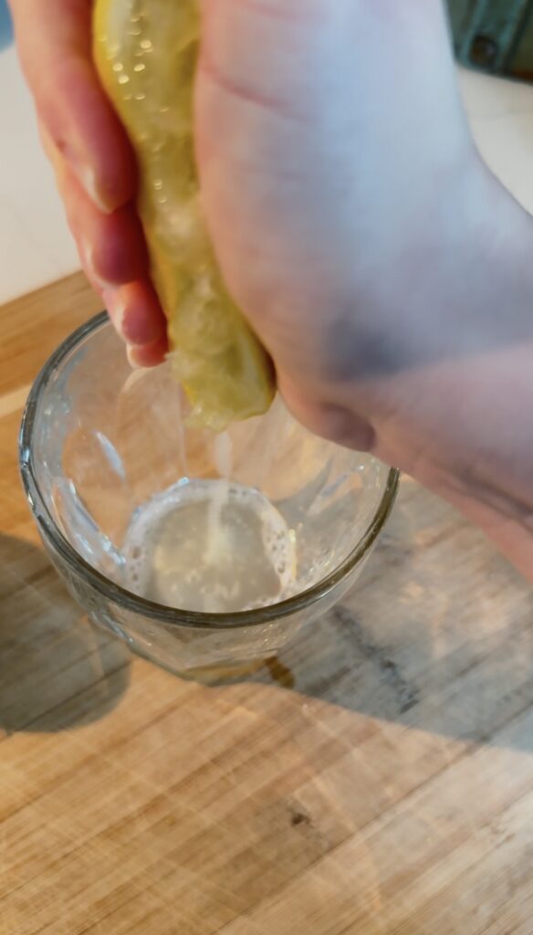juicing a lemon over a cup