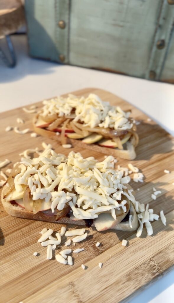 adding mounds of cheese to the bread with fig jam, apple slices, and caramelized onions.