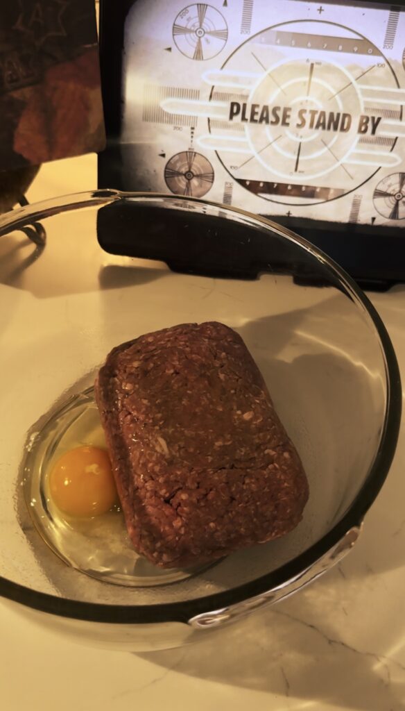 2 lbs or ground beef with an egg in a glass bowl.