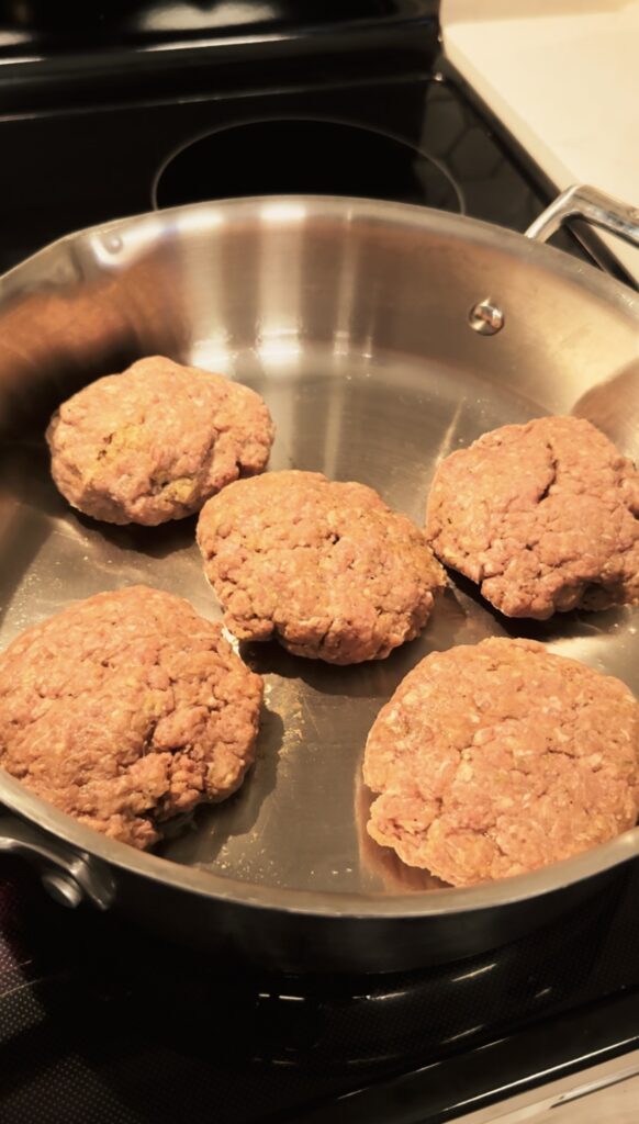 Raw beef patties in a pan.