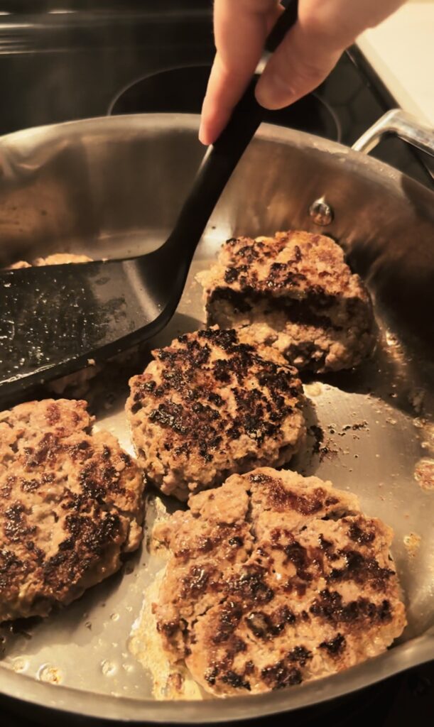Beef patties browned on both sides in the pan