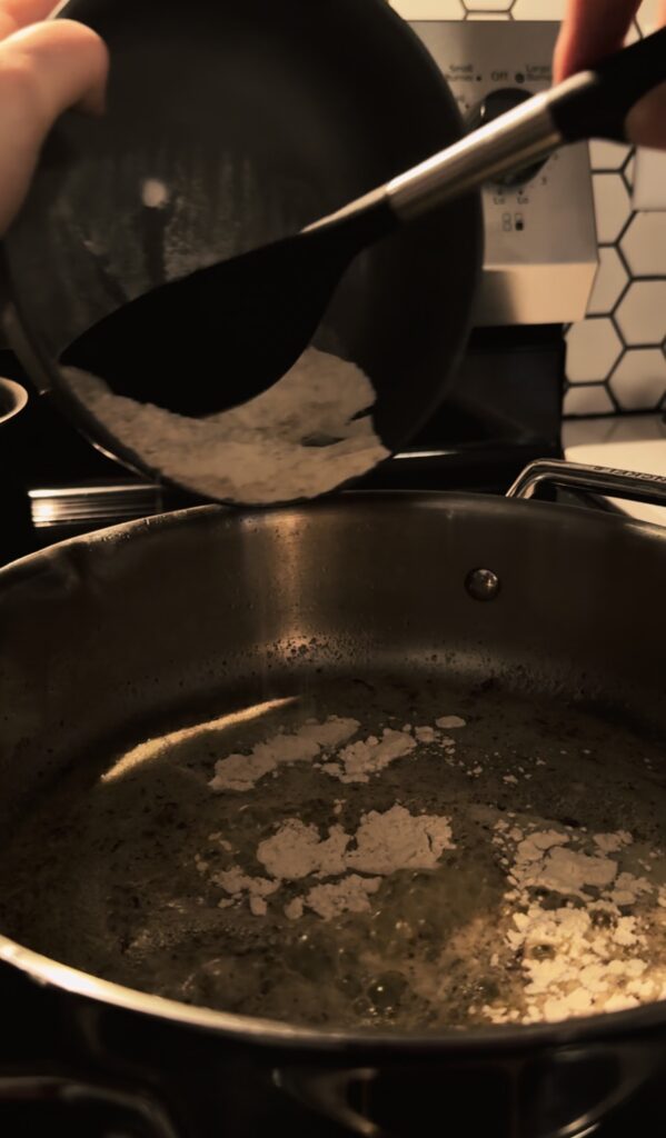 Adding flour and spices to the melted butter to make a roux