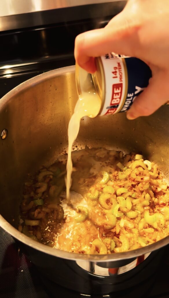 clam juice being poured into the soup